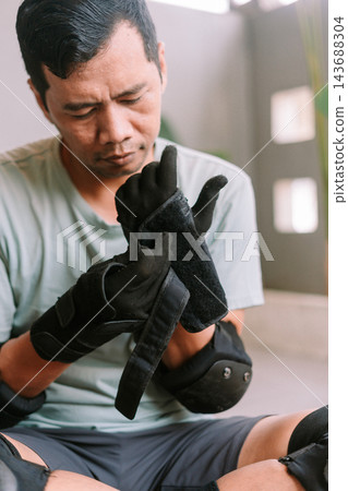 Person preparing for roller skating by putting on protective gear Person preparing for roller skating by putting on protective gear 143688304