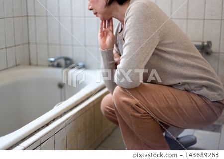中老年婦女對二手房裡老舊的浴室感到不滿。 中老年婦女對二手房裡老舊的浴室感到不滿。 143689263