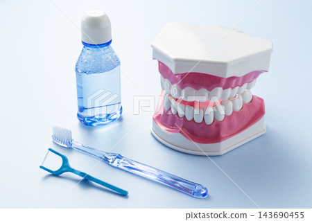 A dental model and dental care products against a blue background. A dental model and dental care products against a blue background. 143690455