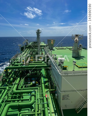 High angle view of a cargo piping system on the deck of an industrial oil tanker ship sailing in open sea. High angle view of a cargo piping system on the deck of an industrial oil tanker ship sailing in open sea. 143690590