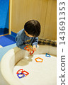 A boy engrossed in educational toys indoors. 143691353