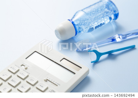藍色背景上擺放著計算器和牙科護理產品。 143692494