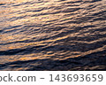 暮色溫暖的光芒灑在水面和波浪上。 143693659