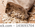 oat flakes cereal in burlap sack on wooden table. 143693704