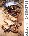 Dry mushrooms in jar on wooden table. 143693713