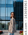 Attractive Woman Standing Near Modern Office Building Wearing Beige Blazer Looking Aside. Casual Business Lifestyle Concept Female Urban Portrait 143694963