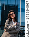 Beautiful Woman Standing Near Modern Office Building Wearing Beige Blazer And Glasses. Casual Business Lifestyle Concept Female Urban Portrait 143694967