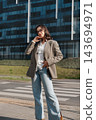 Pretty Woman Standing Near Office Building Wearing Beige Blazer And Jeans Talking On Smartphone. Casual Business Lifestyle Concept Female Urban Style 143694971