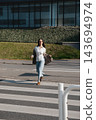 Pretty Woman Running Across Crosswalk Near Modern Office Building Wearing Beige Blazer And Jeans. Casual Business Lifestyle Concept Female Urban 143694974
