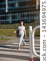 Beautiful Woman Walking Across Street Near Modern Office Building Wearing Beige Blazer And Jeans. Casual Business Lifestyle Concept Female Urban 143694975