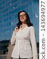 Beautiful Woman In White Shirt And Glasses Holding Blazer Near Modern Office Building. Casual Business Lifestyle Concept Female Urban Style 143694977