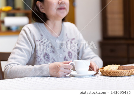 中老年婦女在客廳享受下午茶時光。 中老年婦女在客廳享受下午茶時光。 143695485