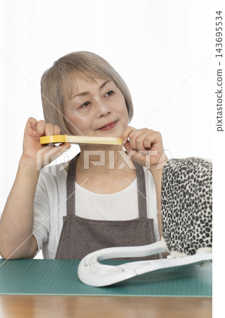一位老婦人在客廳裡改造了一個娃娃椅，作為她的DIY愛好。 143695534