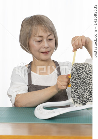 一位老婦人在客廳裡改造了一個娃娃椅,作為她的DIY愛好。 一位老婦人在客廳裡改造了一個娃娃椅,作為她的DIY愛好。 143695535
