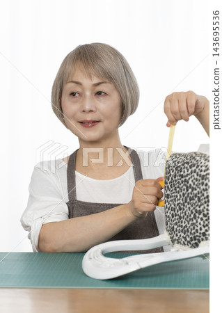 一位老婦人在客廳裡改造了一個娃娃椅,作為她的DIY愛好。 一位老婦人在客廳裡改造了一個娃娃椅,作為她的DIY愛好。 143695536