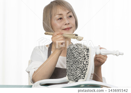 一位老婦人在客廳裡改造了一個娃娃椅,作為她的DIY愛好。 一位老婦人在客廳裡改造了一個娃娃椅,作為她的DIY愛好。 143695542