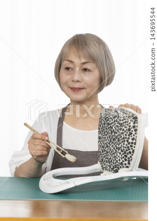 一位老婦人在客廳裡改造了一個娃娃椅，作為她的DIY愛好。 143695544