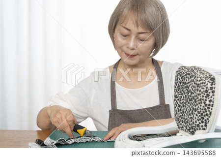 一位老婦人在客廳裡改造了一個娃娃椅,作為她的DIY愛好。 一位老婦人在客廳裡改造了一個娃娃椅,作為她的DIY愛好。 143695588