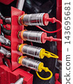 Hydraulic hose fittings on a red machinery panel in a workshop during equipment maintenance 143695681