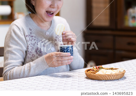中老年婦女在客廳享受下午茶時光。 中老年婦女在客廳享受下午茶時光。 143695823