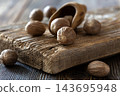 Whole nutmeg seeds scattered on rustic wooden surface with shell 143695948