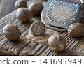Whole nutmeg seeds and grated nutmeg on rustic wooden surface 143695949