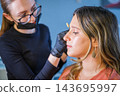 In a beauty salon, the treatment focuses on eyebrow lamination, a beautician, an esthetician, eyebrow tinting, a young woman, and brow styling 143695997
