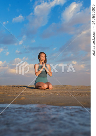 Beach scene featuring a woman, yoga, vajrasana, thunderbolt pose, meditating, and prayer pose Beach scene featuring a woman, yoga, vajrasana, thunderbolt pose, meditating, and prayer pose 143696009