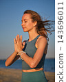 With eyes closed, a woman holds the yoga Prayer Gesture, Namaskar Mudra, at her chest in a side portrait against the open blue sky 143696011