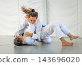 A Brazilian jiu jitsu student attempts a bridging escape from the bottom while her partner maintains top control on the tatami 143696020