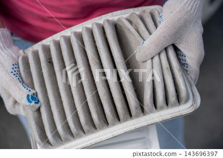 A woman shows a dirty car engine air filter. 143696397