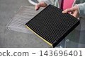 A woman compares old and new cabin air filters. 143696401