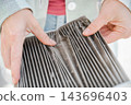 A woman shows a dirty car cabin air filter. 143696403