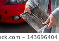 A woman shows a dirty car cabin air filter. 143696404