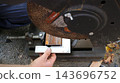 A worker places a metal square against a section of tubing held in a vise to check the angle accuracy before making a cut. The machine is equipped with a chop saw featuring a large abrasive disc. 143696752