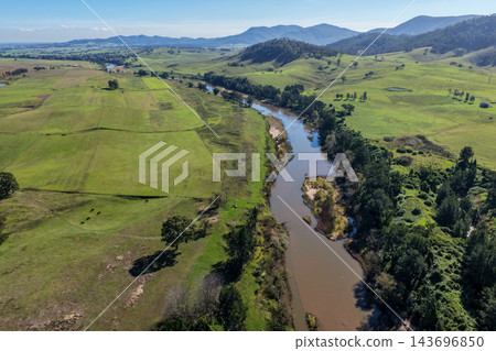 Aerial view of a winding river through green farmland, with wooded riverbanks and rolling hills in Lambs Valley, Hunter Valley, New South Wales, Australia. Aerial view of a winding river through green farmland, with wooded riverbanks and rolling hills in Lambs Valley, Hunter Valley, New South Wales, Australia. 143696850