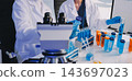 Medical or scientific researcher or man doctor looking at a test tube of clear solution in a laboratory 143697023