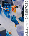 Medical or scientific researcher or man doctor looking at a test tube of clear solution in a laboratory 143697029