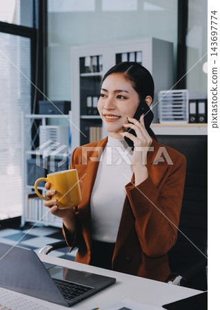 Two Asian businesswomen discussing work while walking outside a modern office building, one holding a digital tablet Two Asian businesswomen discussing work while walking outside a modern office building, one holding a digital tablet 143697774