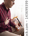 Older Man Experiencing Chest Pain and Holding Medication at Home 143699399