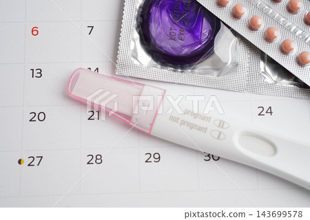 Pregnancy test with birth control pills and condom for female on calendar, ovulation day. 143699578