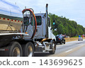 Tanker truck, pickup, cars travel on highway beside trees in daylight. 143699625