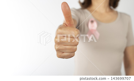Woman Giving Thumbs Up with Pink Breast Cancer Awareness Ribbon on White Background 143699707