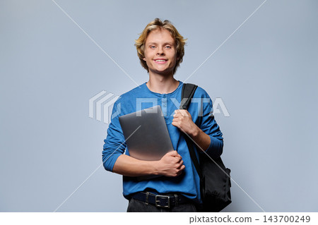 Smiling teenage student boy with backpack and textbook notebook against grey background Smiling teenage student boy with backpack and textbook notebook against grey background 143700249