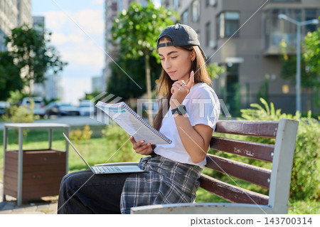 Young woman student studying with laptop notebook outdoors park bench Young woman student studying with laptop notebook outdoors park bench 143700314