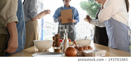 學生在烹飪課上邊聽老師講課邊做筆記。 學生在烹飪課上邊聽老師講課邊做筆記。 143701865