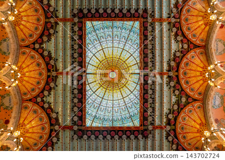 Stained glass skylight with golden sunburst, ceramic roses and orange ceiling domes in Palau de la Musica Catalana, Barcelona 143702724