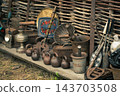 Vintage forged metal tools and antique household items displayed at a local blacksmith craft fair against a rustic wattle fence, selective focus. 143703508