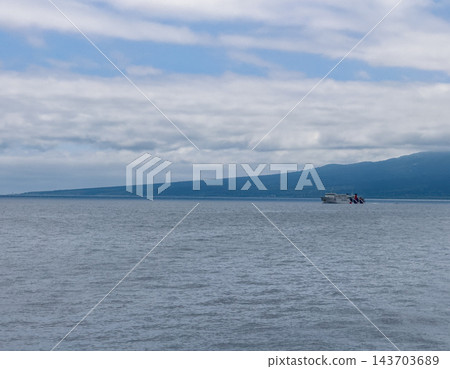 【北海道】一艘小船在利尻島海岸和雲霧繚繞的山麓間航行。 【北海道】一艘小船在利尻島海岸和雲霧繚繞的山麓間航行。 143703689