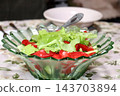 Clear glass salad bowl containing a salad of fresh vegetables and herbs 143703894